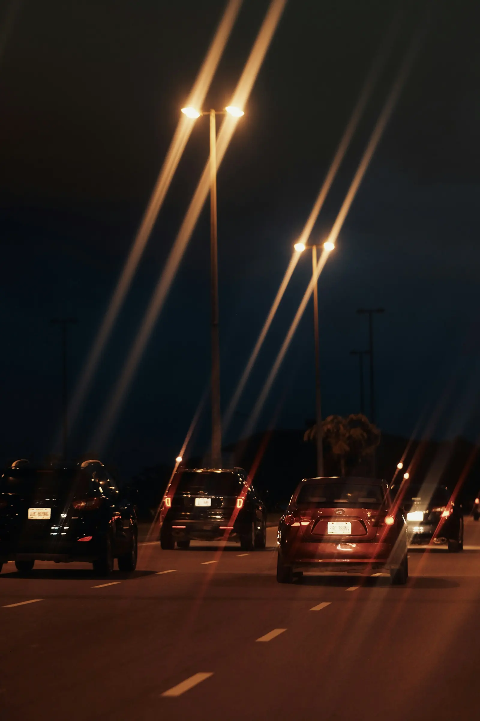 Cars on an Abuja road at night under tall streetlights